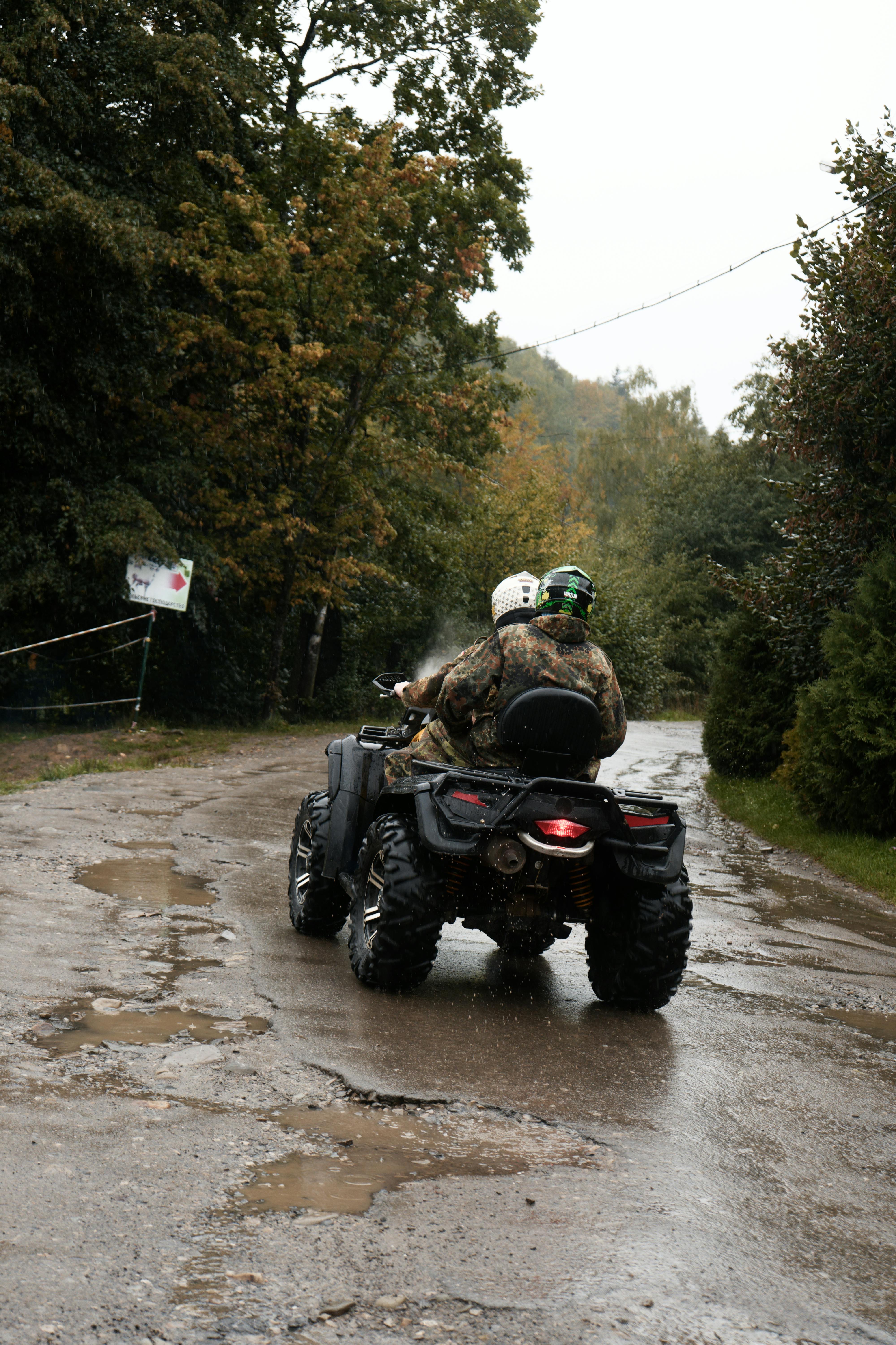 two men riding four wheelers in the rain